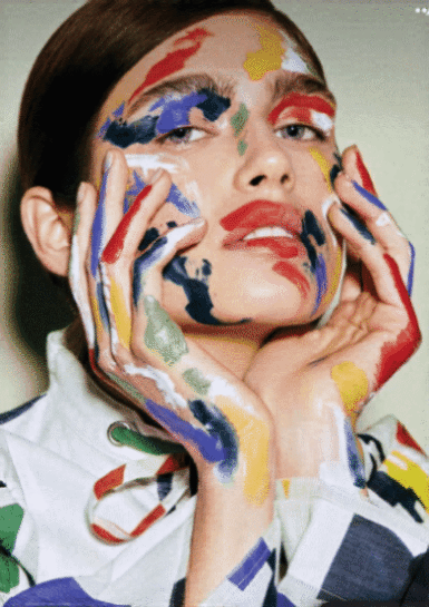 Mujer con las manos en la cara y pintura de diferentes colores que representan las emociones y su proceso para gestionarlas